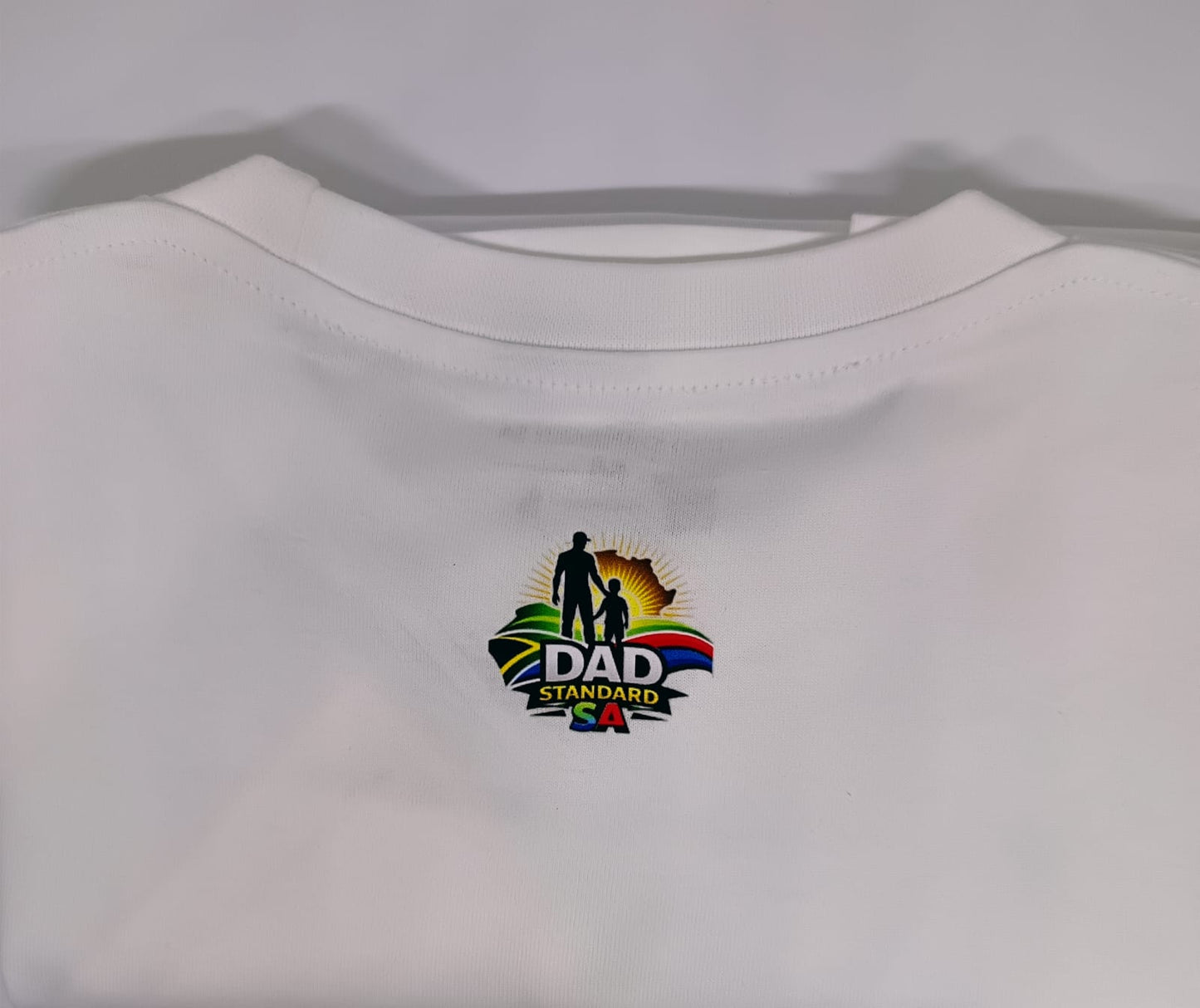White t-shirt with a colorful 'DAD Standard' logo on a light gray background