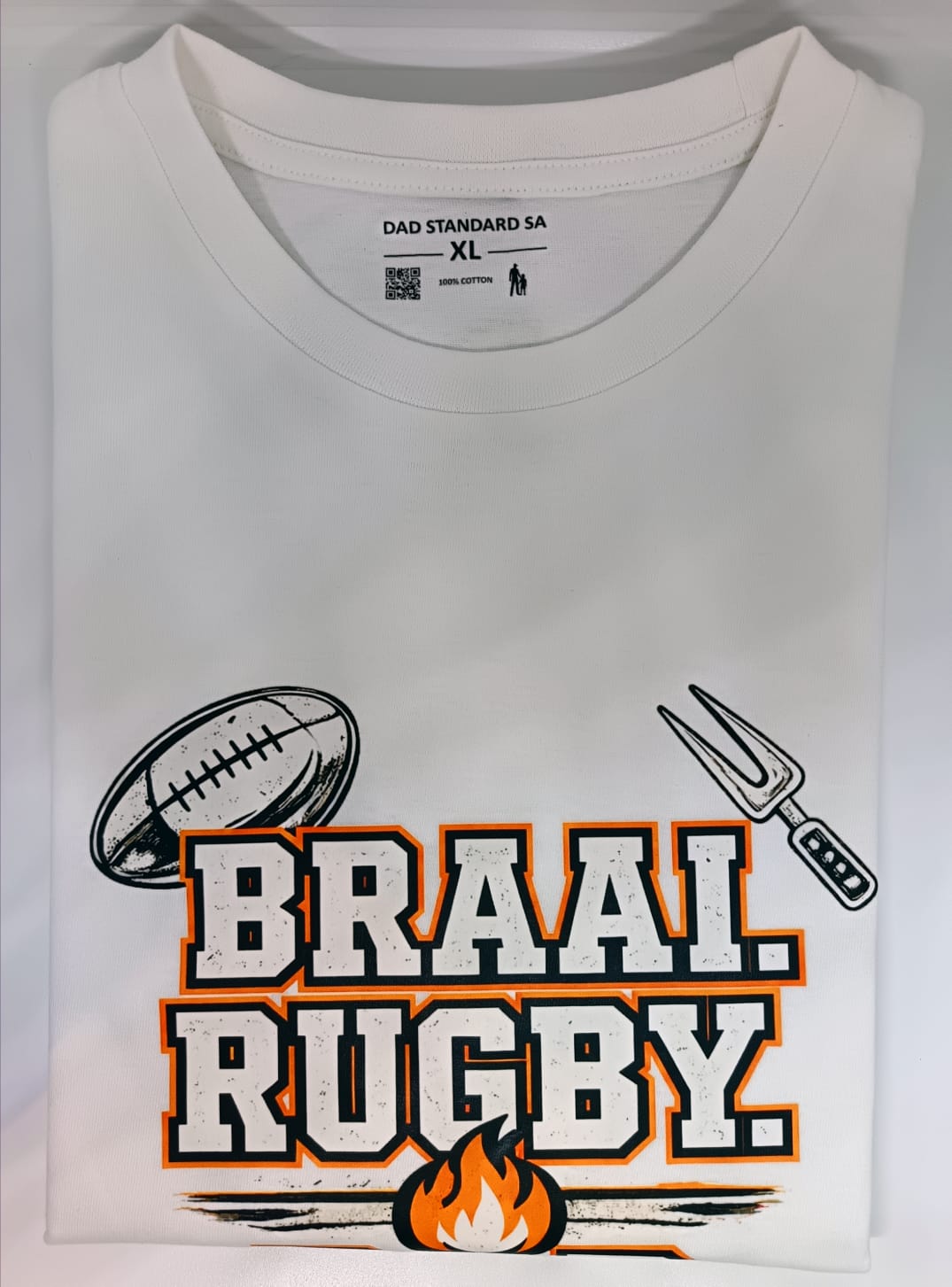 White t-shirt with 'BRAAI RUGBY' design featuring a rugby ball, fork, and flame on a white background.