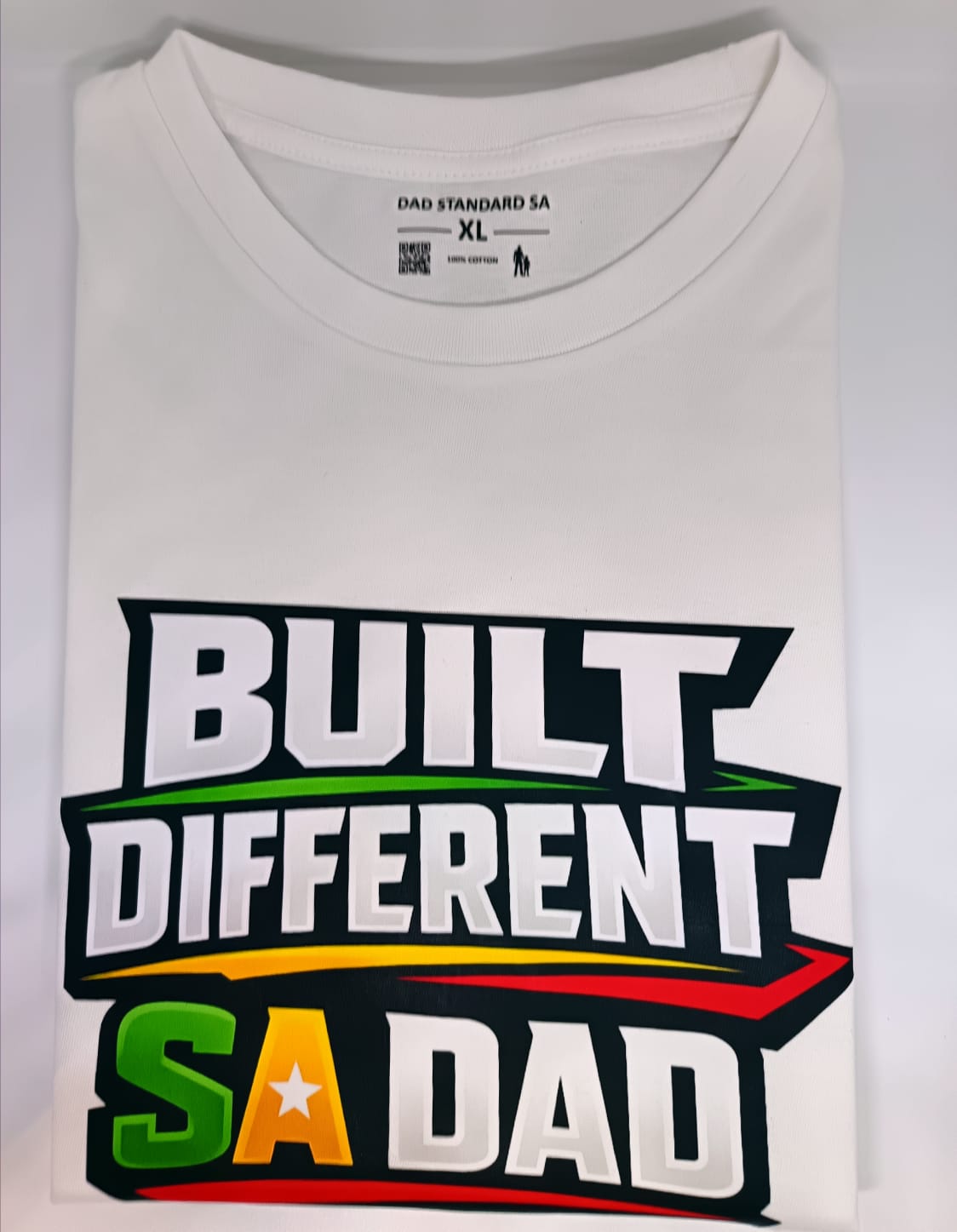 White t-shirt with 'Built Different SA Dad' text design on a white background